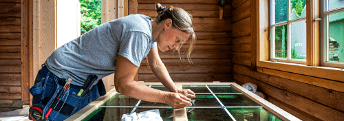 En kvinna renoverar ett fönster med gröna glas